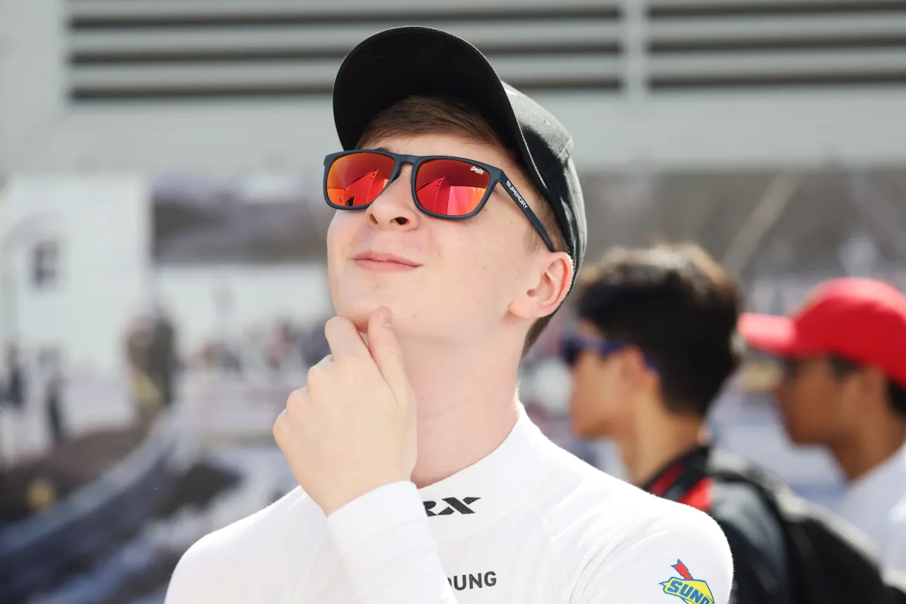 Noah Young on the grid wearing a cap and sunglasses before a race